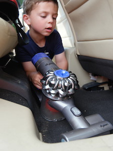 Kid cleaning car with Dyson V6 Absolute Cordless Handled Vacuum