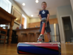 Kid cleaning hardwood floor with Dyson V6 Absolute Cordless Handled Vacuum